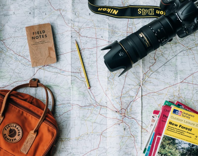 A backpack, camera and notebook on a travel map